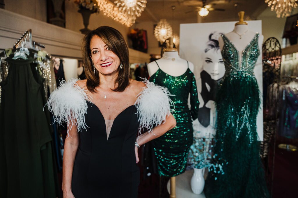 The owner of Special Occasions on the Avenue showcasing a gorgeous formal dress with feather sleeves in her shop in Batavia Illinois. 
